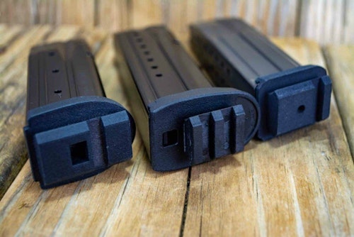 The left and right magazines show replacement baseplates for Sig Sauer P320 and P229 magazines. The center Smith & Wesson M&P magazine has a universal baseplate attached to the standard magazine.